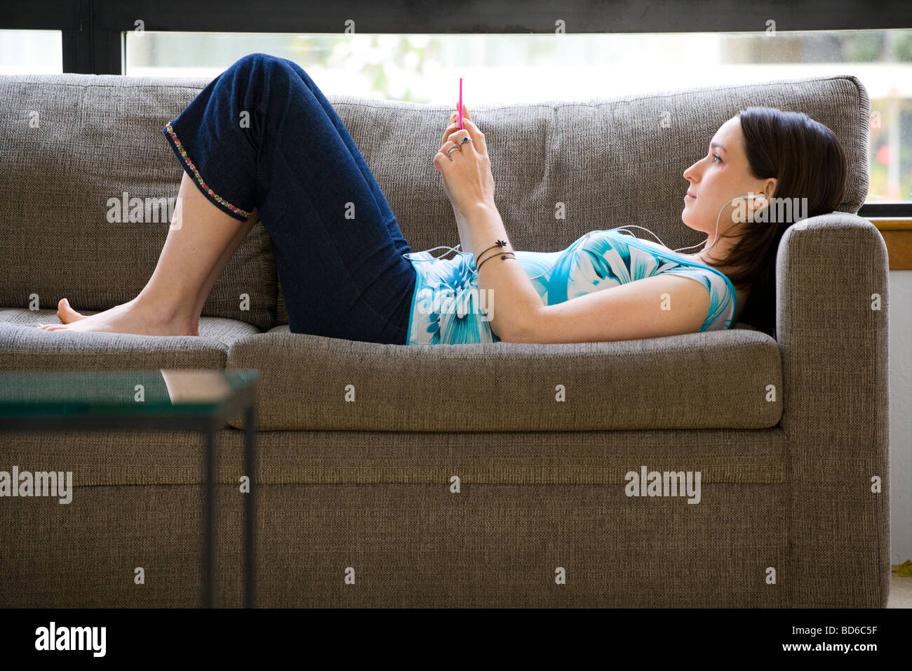 Femme sur canapé à l'écoute de son Ipod Banque D'Images