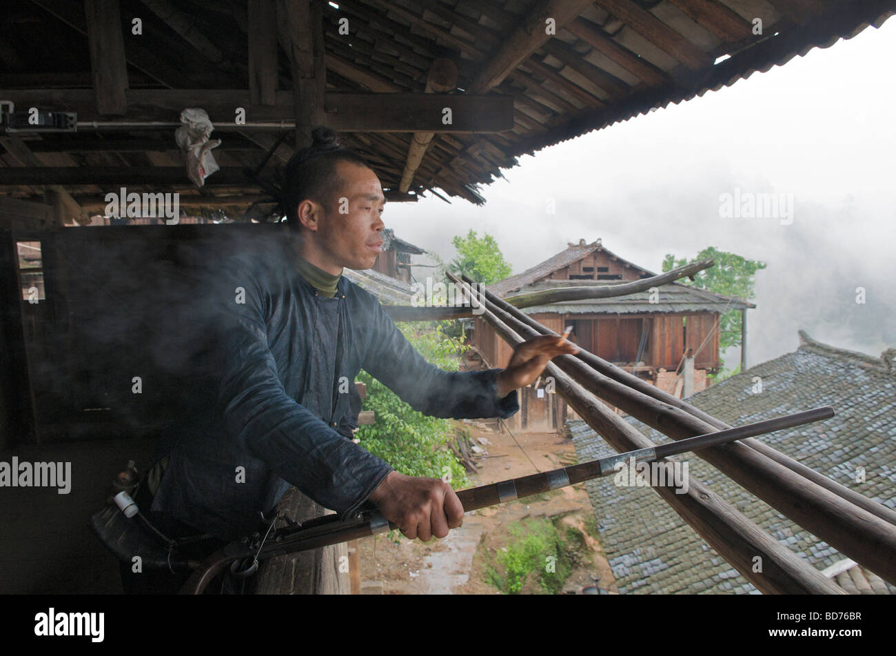 L'homme d'armes à feu avec Miao Basha contempler plus de village du comté de la province du Guizhou Chine Congjiang Banque D'Images