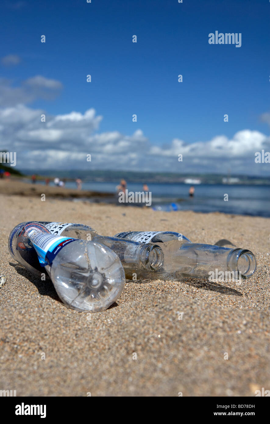 Les bouteilles de bière vides et bouteille plastique jetés jonchent une plage dans le comté de Down en Irlande du Nord uk Banque D'Images