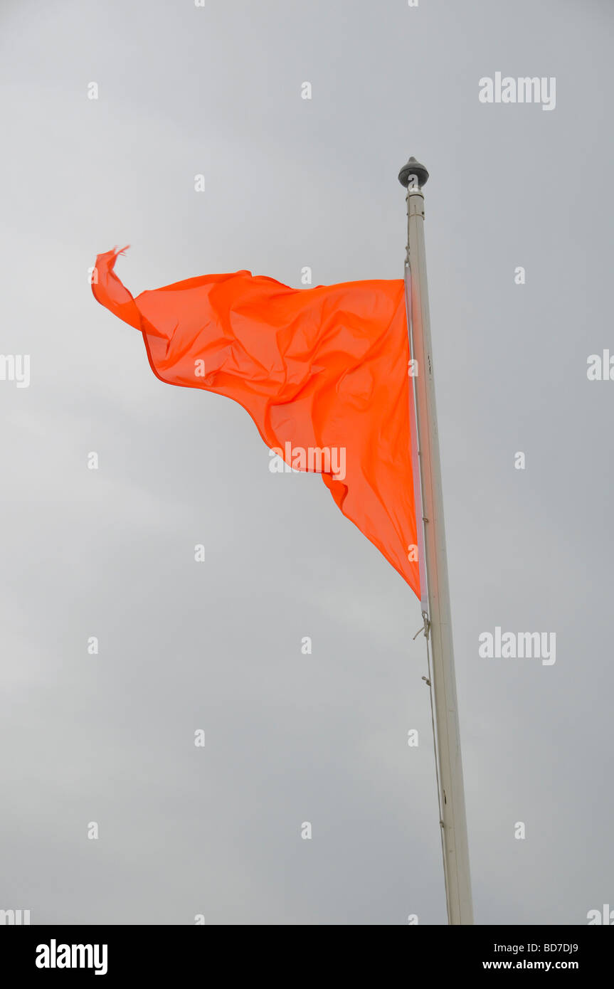 Drapeau Orange volant dans le vent dans le ciel gris Banque D'Images