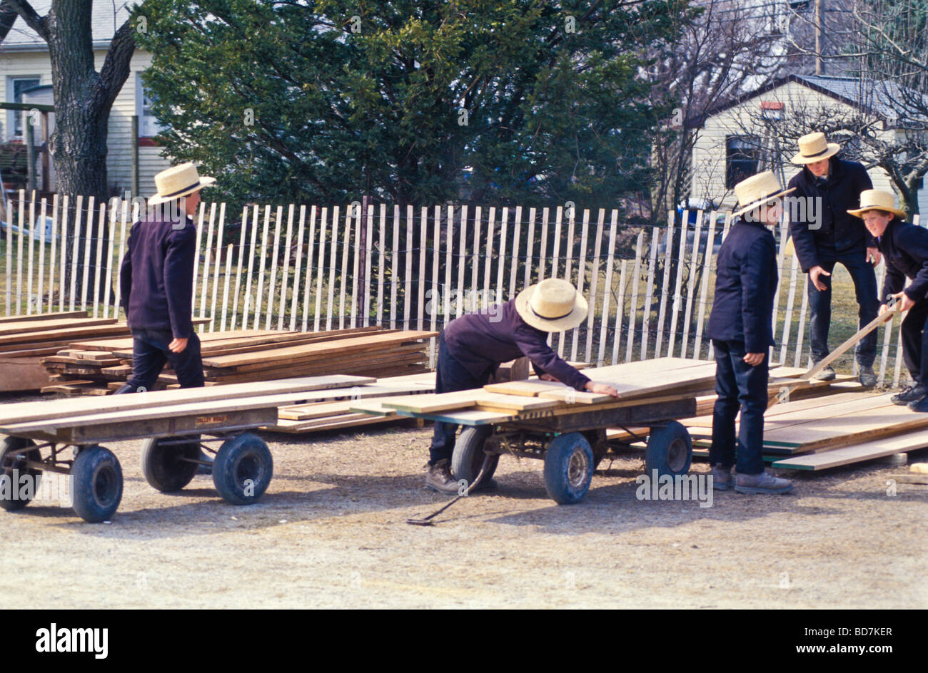 Groupe de jeunes garçons de ferme amish sur bois charge chariot à Lancaster County boue printemps vente aux enchères. Banque D'Images