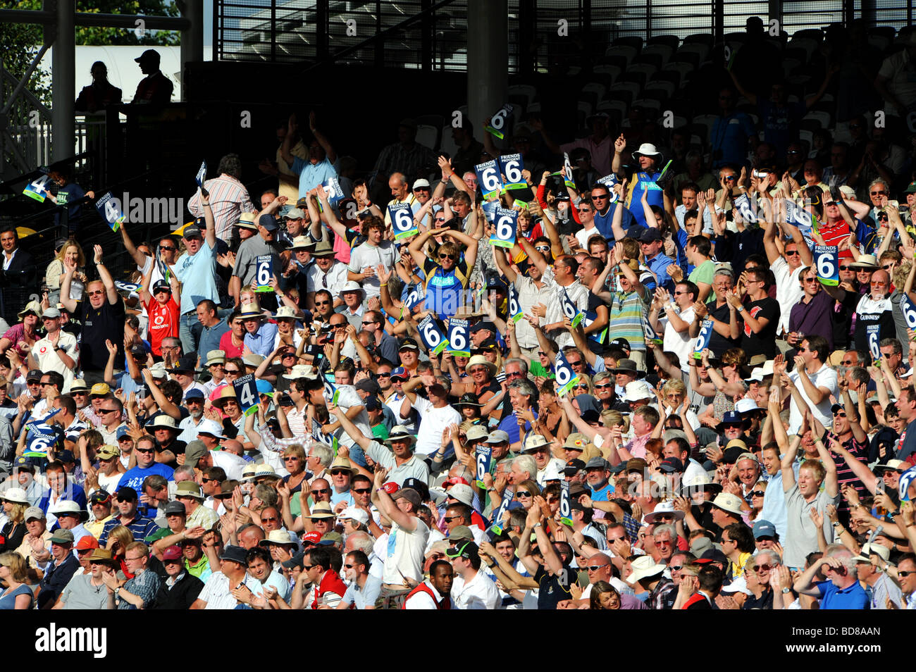 Les membres de la foule à un match de cricket Lord's hold up quelques six signes Banque D'Images