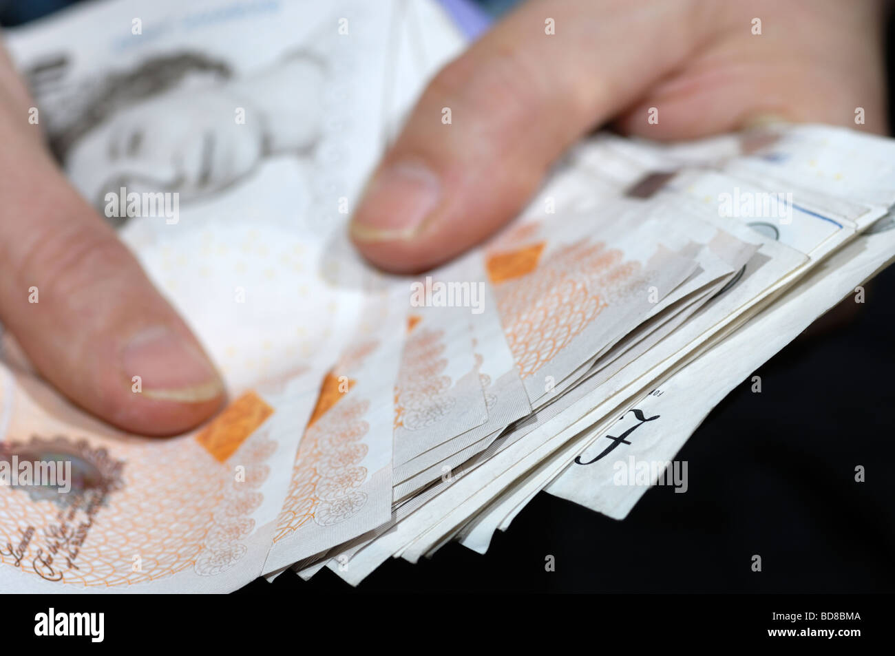 Mains tenant une liasse de billets de banque sterling britannique Banque D'Images