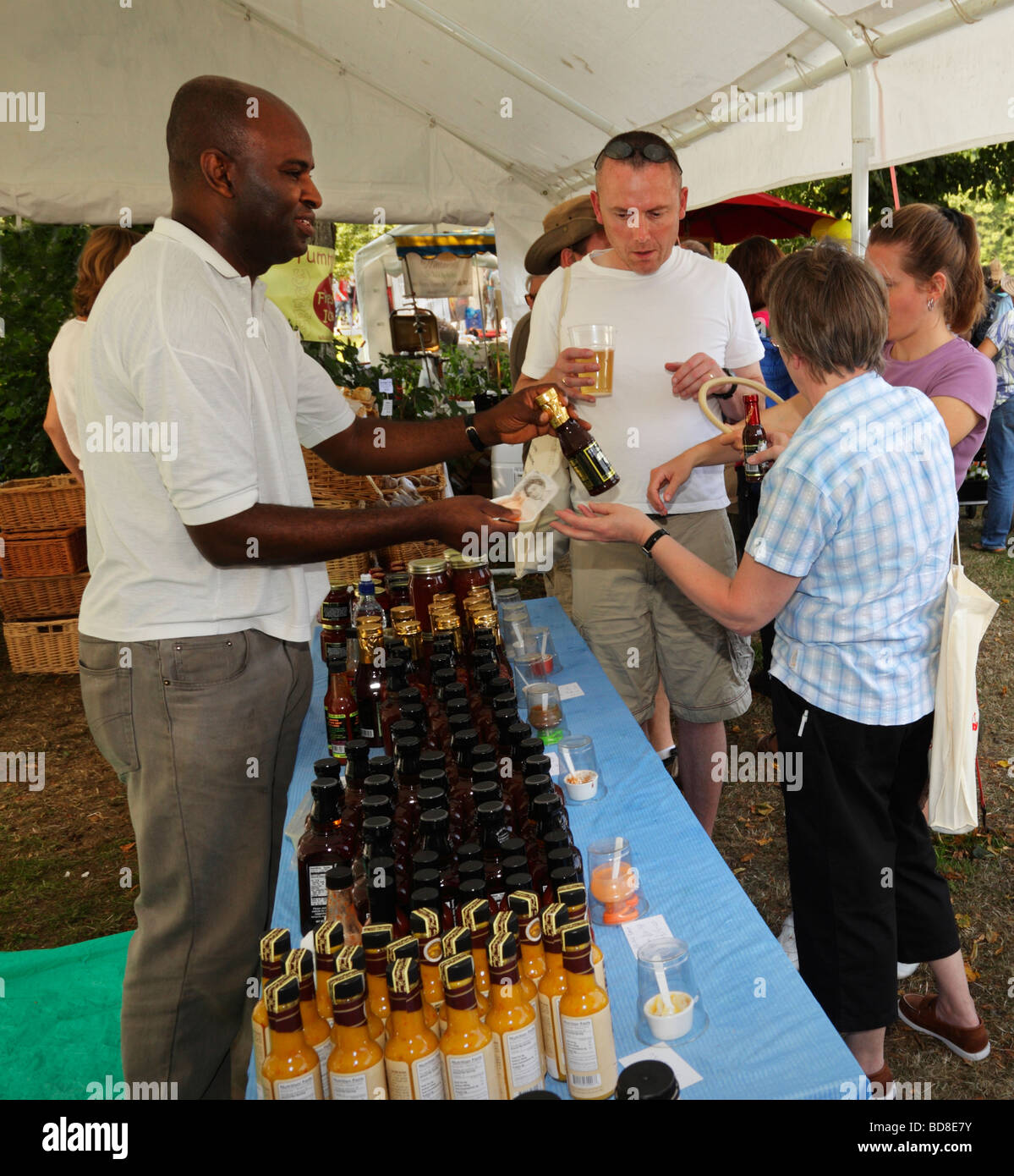 Les gens qui achètent des bouteilles de sauce chili. Doyen de l'Ouest Chili Fiesta, West Sussex, Angleterre, Royaume-Uni. Banque D'Images