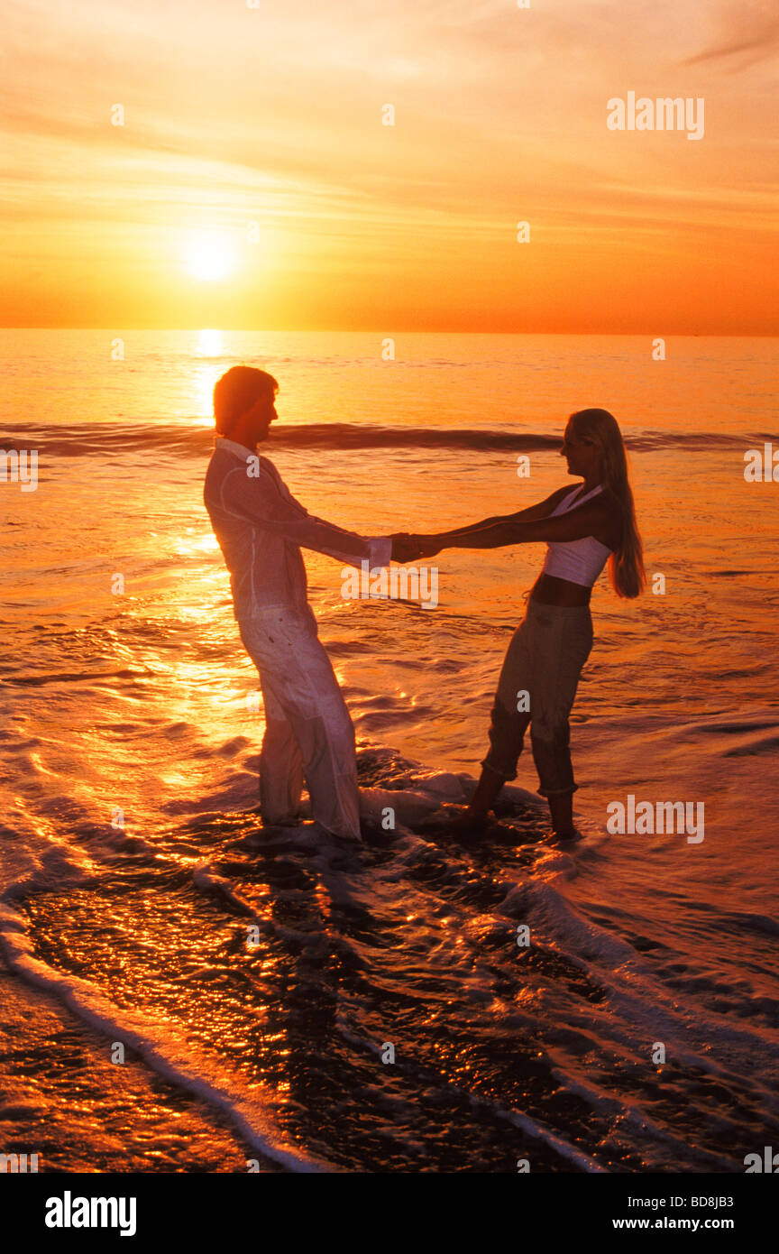 Couple jouant sur la côte de sable au coucher du soleil à Laguna Beach en Californie USA Banque D'Images