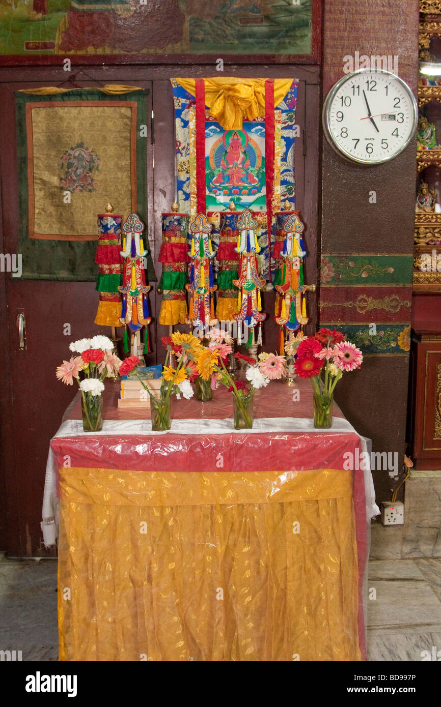 Bodhnath, au Népal. Une table à l'intérieur de l'Tsamchen Gompa (monastère). Un Thangka (peinture bouddhiste Tibétain) est suspendu sur le mur. Banque D'Images