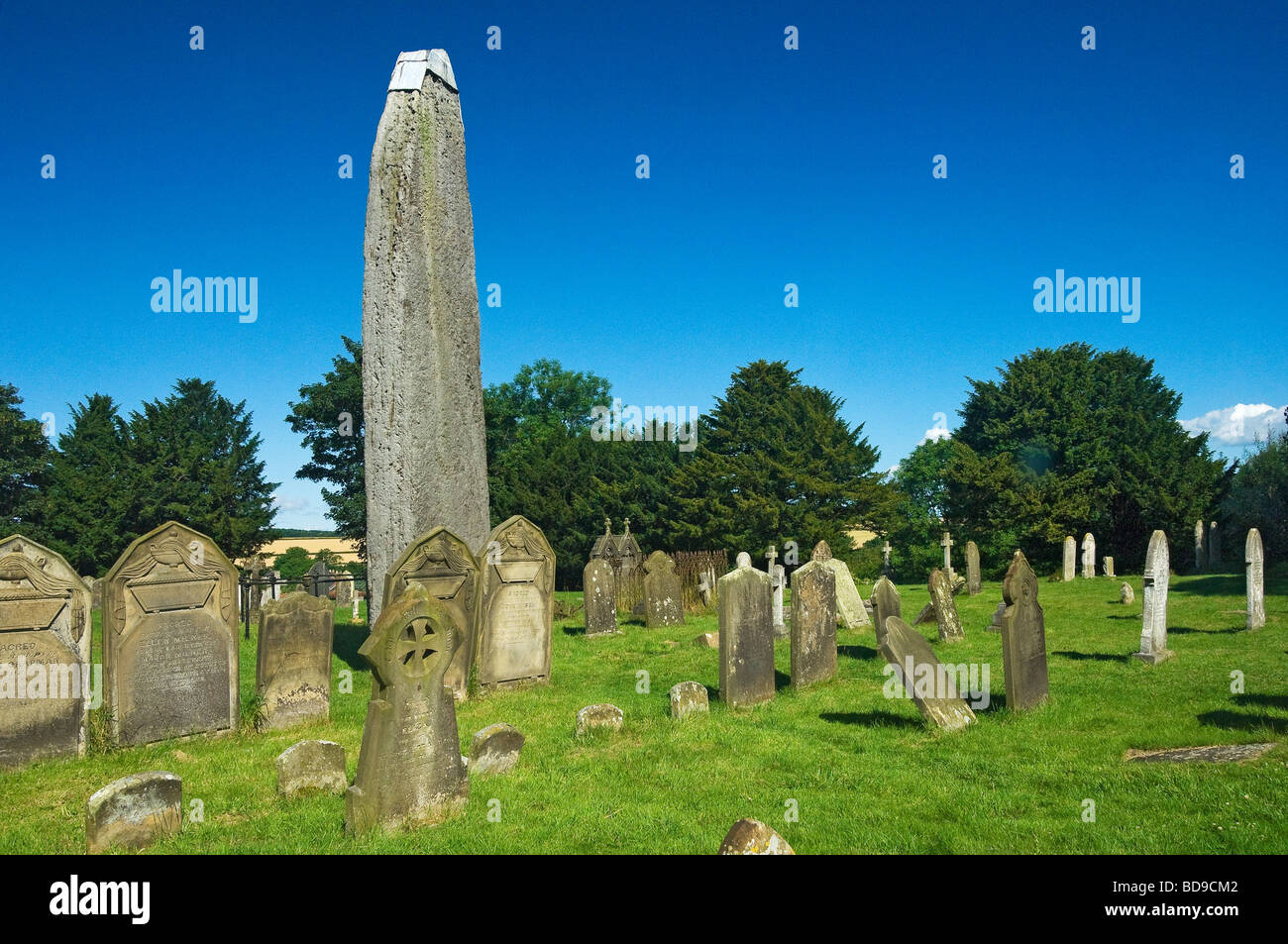 Rudston monolithe de pierre debout et de tombes dans le cimetière de All Saints Church en été East Yorkshire Angleterre Royaume-Uni GB Grande-Bretagne Banque D'Images