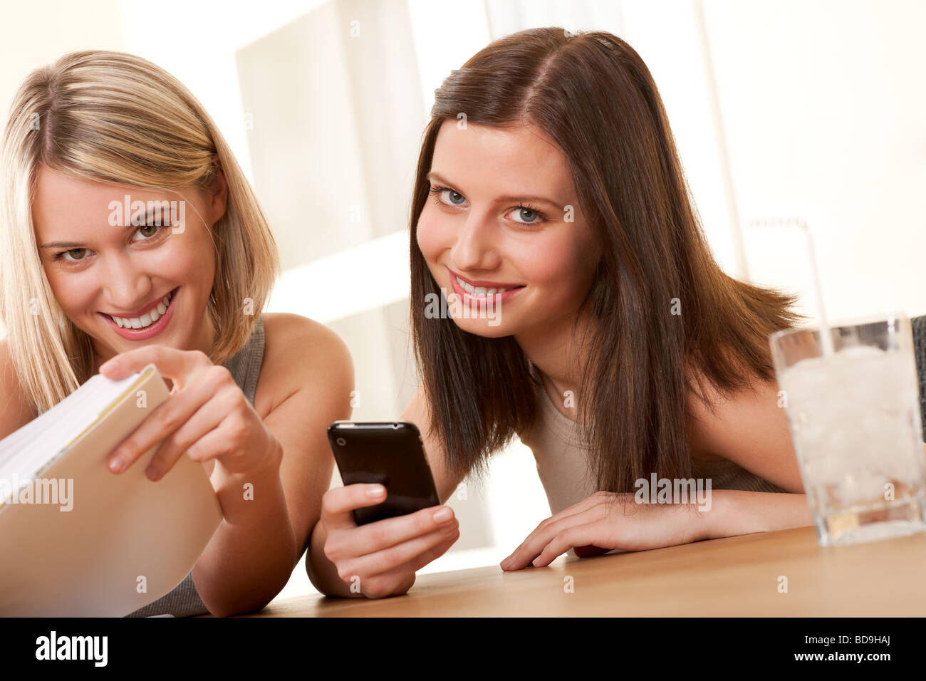 Deux étudiants de profiter de temps libre, souriant avec réserve et téléphone mobile Banque D'Images