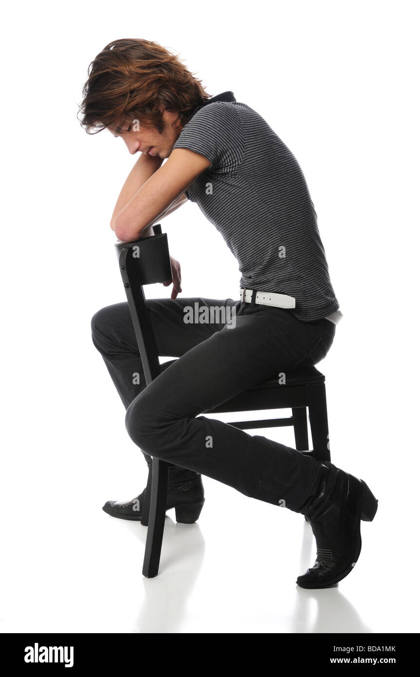 Jeune homme assis sur la chaise noire avec la tête basse Banque D'Images