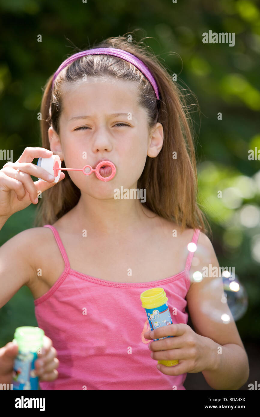 Pretty young girl blowing soap bubbles outdoor le soleil se reflète dans les bulles Banque D'Images