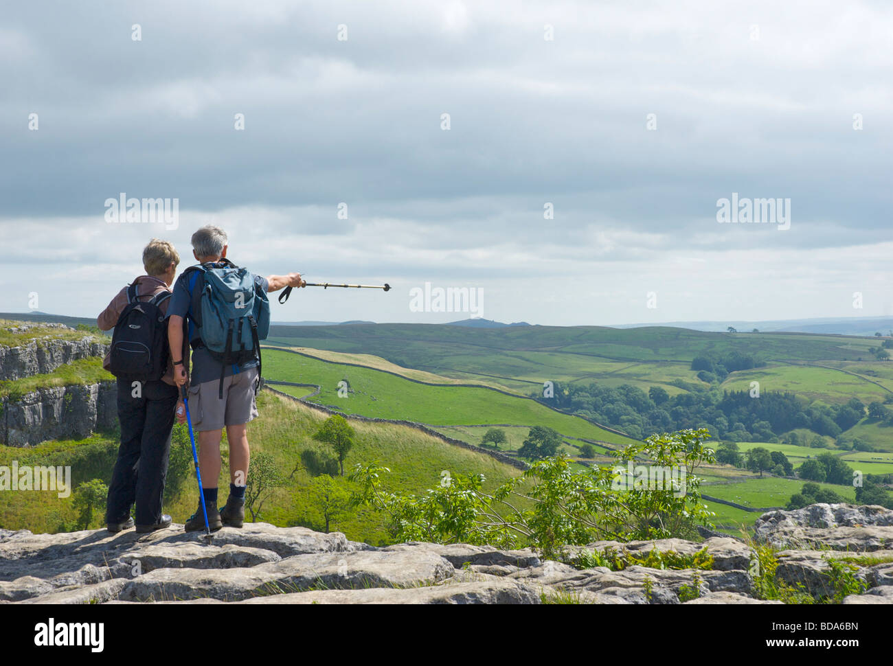 Deux personnes profitant de la vue depuis le haut de Malham Cove, dans le Yorkshire Dales National Park, North Yorkshire, England UK Banque D'Images Deux personnes profitant de la vue depuis le haut de Malham Cove, dans le Yorkshire Dales National Park, North Yorkshire, England UK Banque D'Images