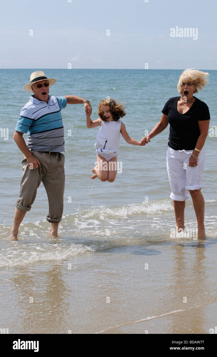Les grands-parents jouer avec vos petits-enfants à la mer sauter et danser dans la mer Banque D'Images