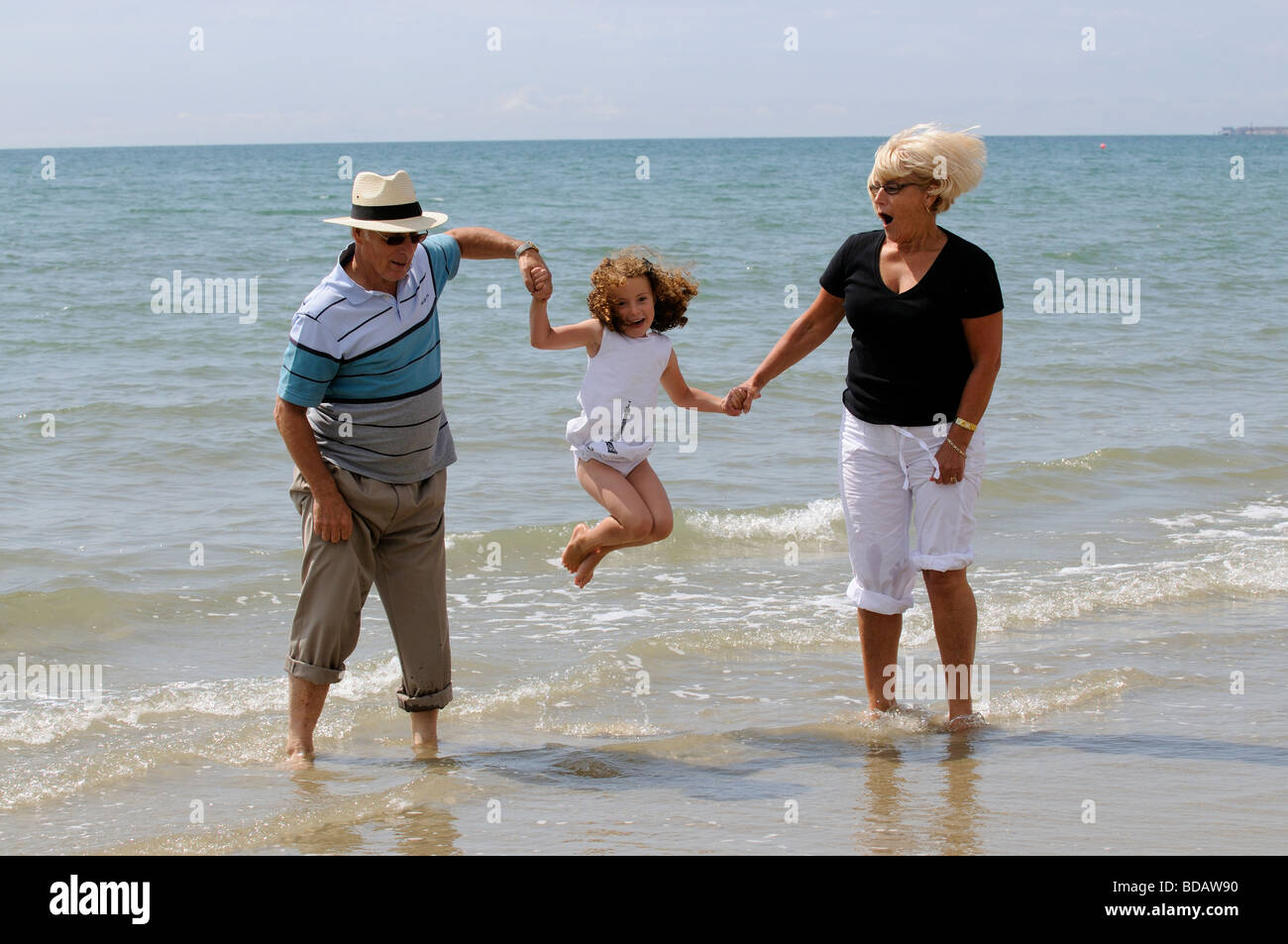 Les grands-parents jouer avec vos petits-enfants à la mer sauter et danser dans la mer Banque D'Images