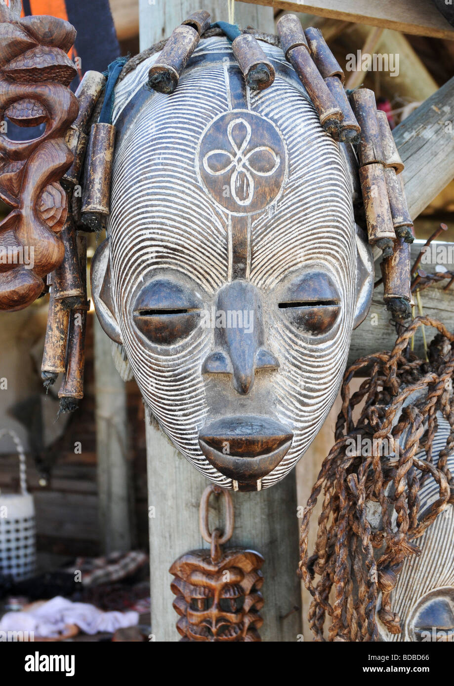 Une main remarquable en bois sculpté et peint masque tribal africain en blanc attaché avec d'autres chef décoration avec chaîne. Banque D'Images