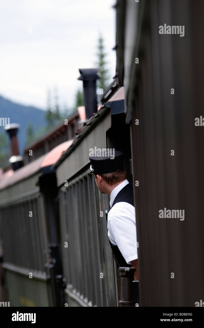 Skagway en Alaska, le frein d'orchestre sur le chemin de fer White Pass and Yukon Route s'appuie d'entre les wagons pour une meilleure vue. Banque D'Images