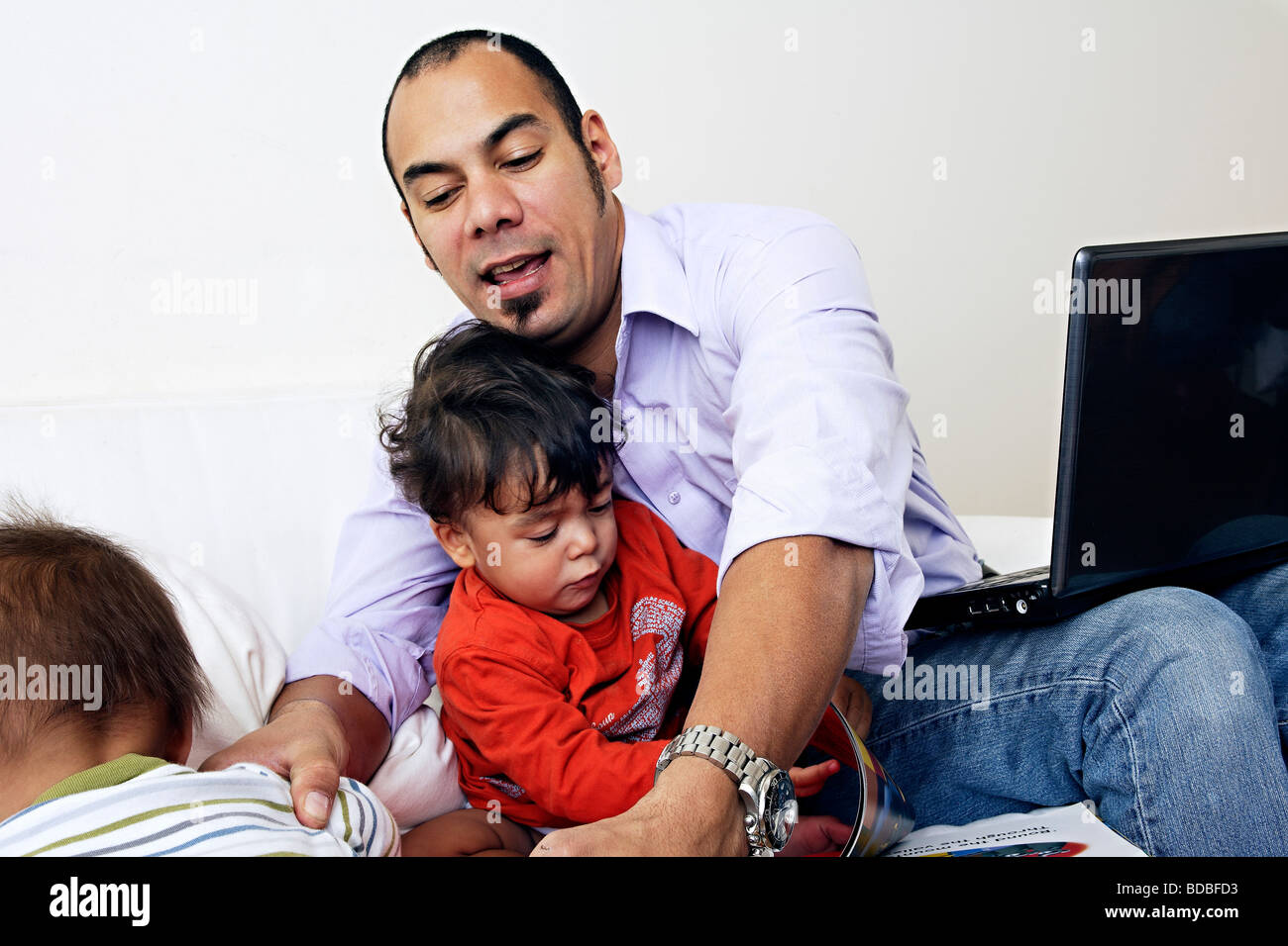 Père sur canapé avec ordinateur portable et ses deux fils Banque D'Images