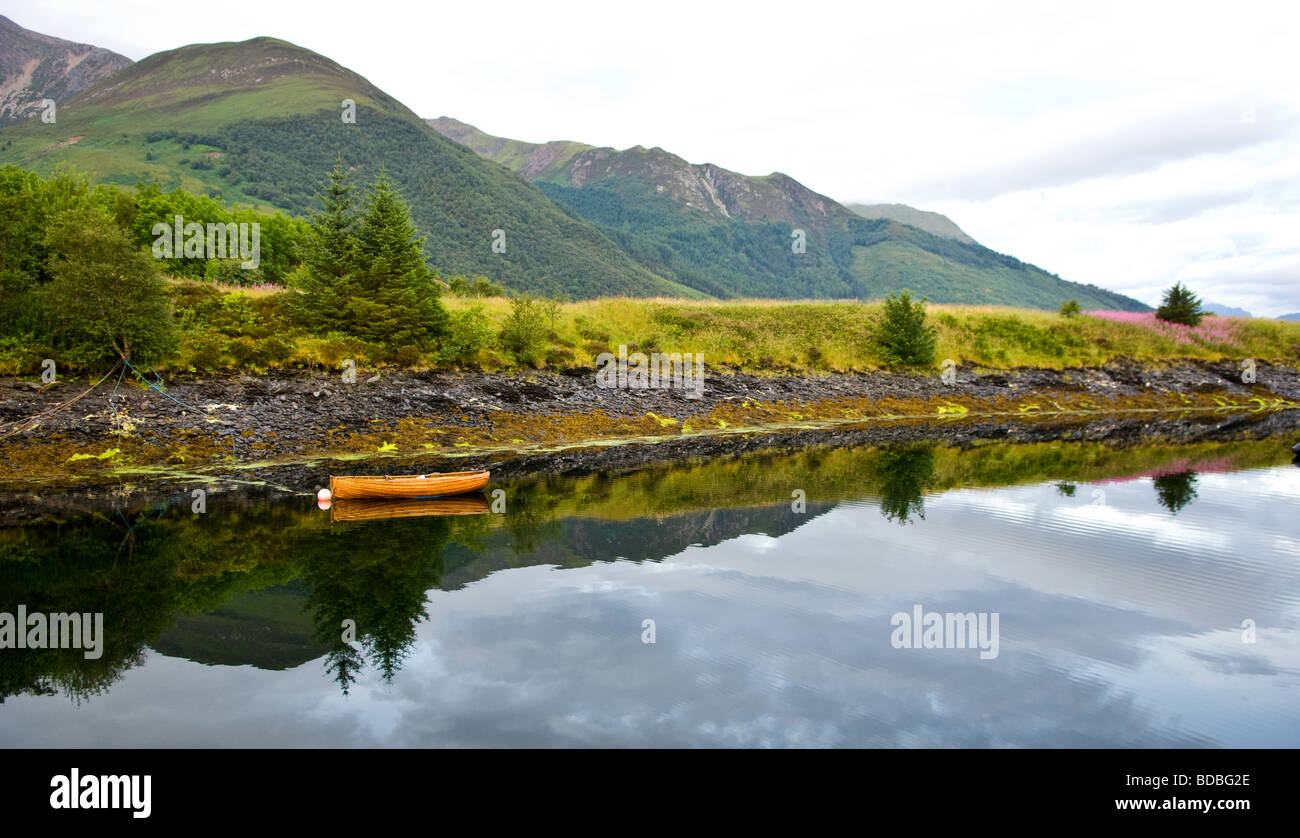 Bateau à rames et sa réflexion mouillée dans une petite baie de Loch Leven, l'Écosse. Banque D'Images
