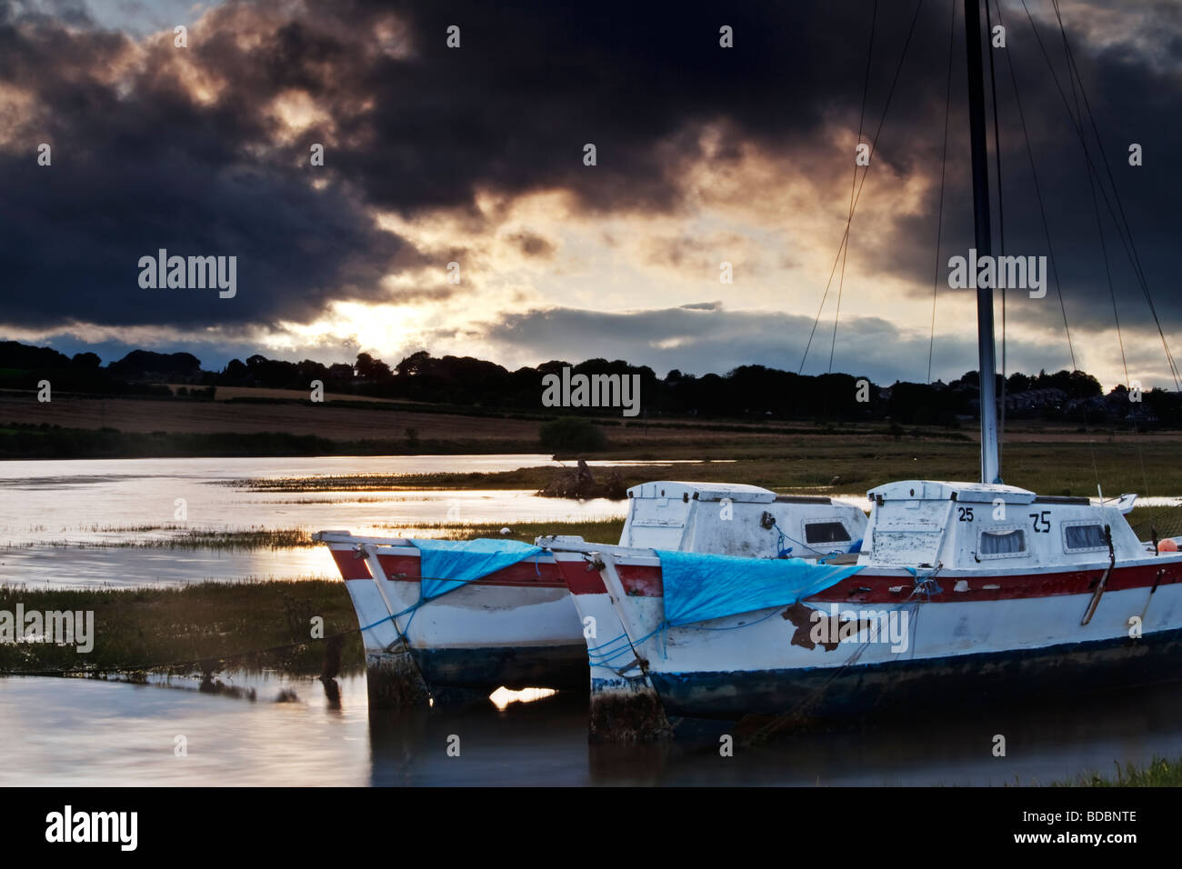 Bimaran double coque voile attaché sur l'estuaire de l'ALN, près du village de Northumbrian Vernonia sur un soir d'été orageux Banque D'Images