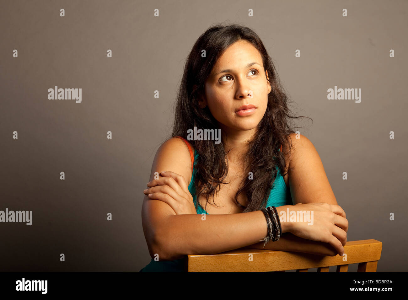 Portrait of Hispanic Latina femme contre l'arrière-plan gris, elle a de graves expression, looking at camera. Banque D'Images