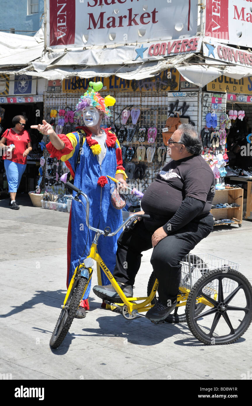 Clown et un gros homme sur un tricycle jaune Banque D'Images