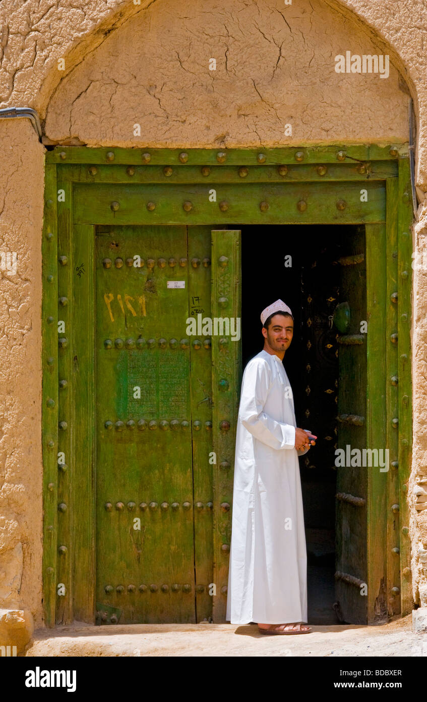 Jeune homme en face de maison traditionnelle faite de boue et de brique dans la ville d'Al Hamra Sultanat d'Oman Banque D'Images