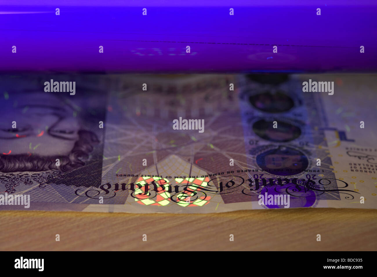 En utilisant un système de lumière noire pour vérifier une note de 20 livres de billets de banque d'Angleterre pour vérifier qu'il est authentique Banque D'Images