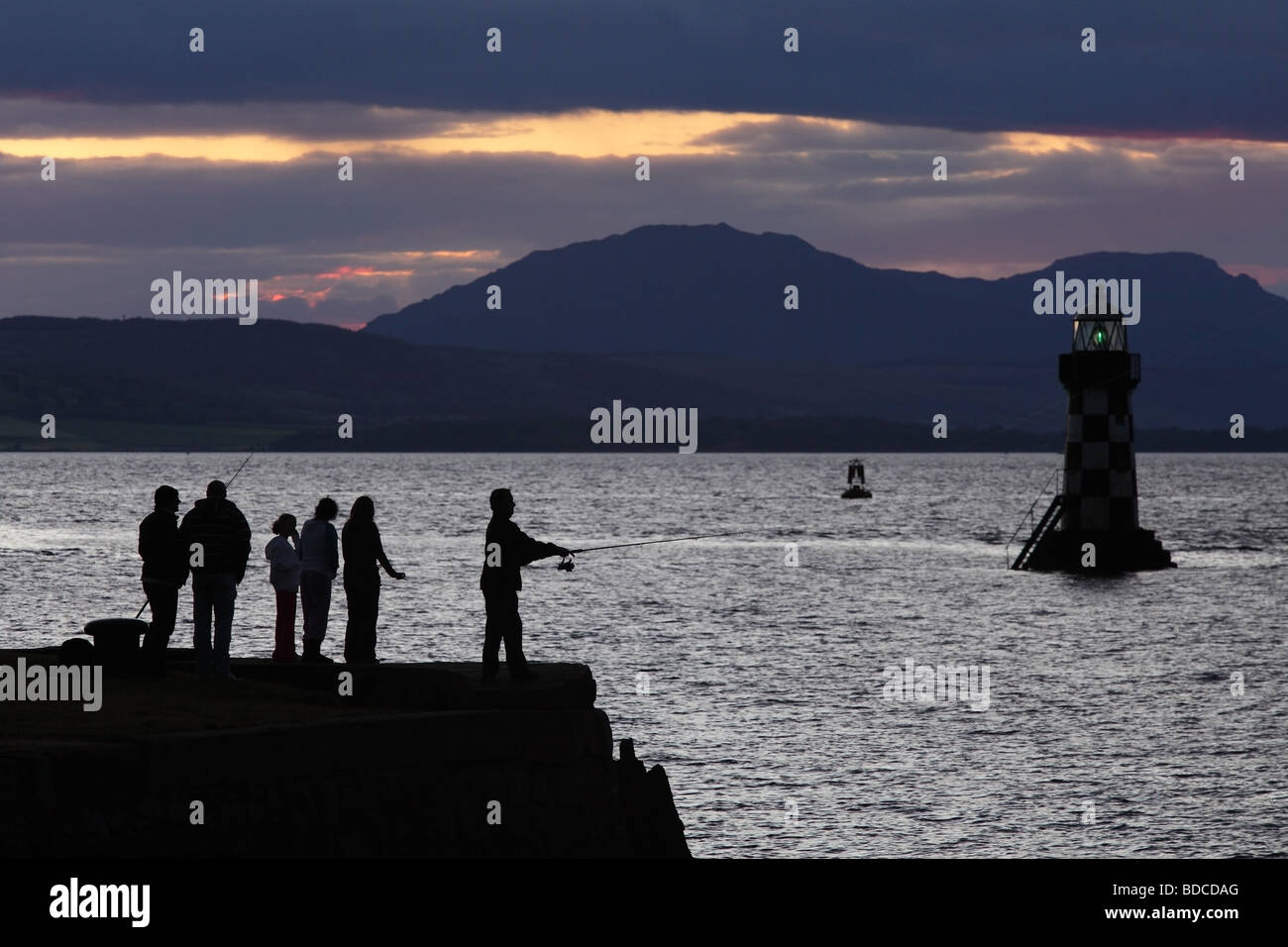 Groupe de personnes pêchant au coucher du soleil sur le Firth of Clyde, Port Glasgow, Écosse, Royaume-Uni Banque D'Images