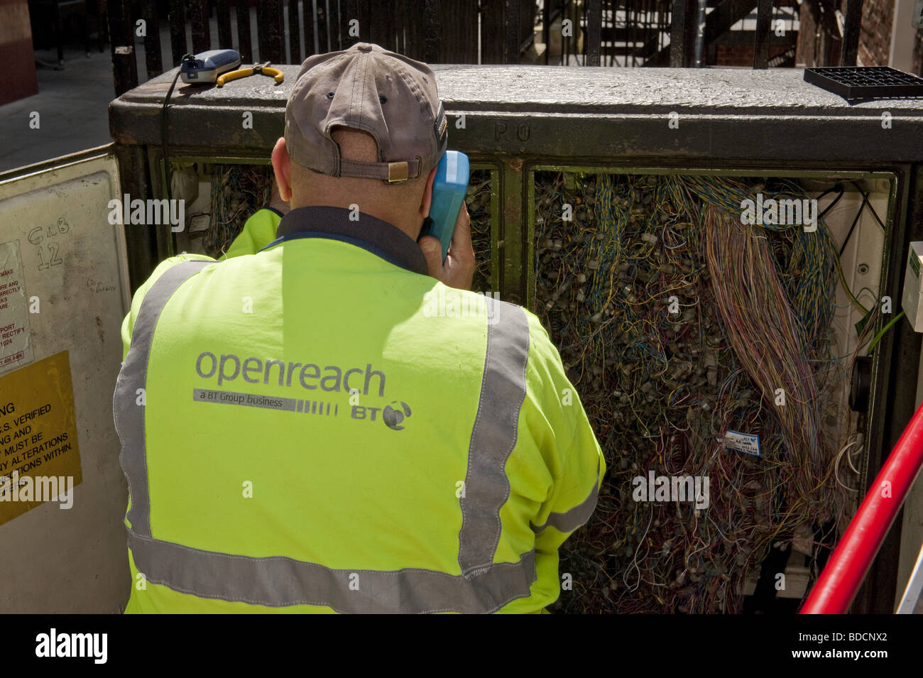 À la recherche sur l'épaulement de British Telecom BT Outreach ingénieur travaillant sur le téléphone en face de libre échange / boîte de connexion de câblage Banque D'Images