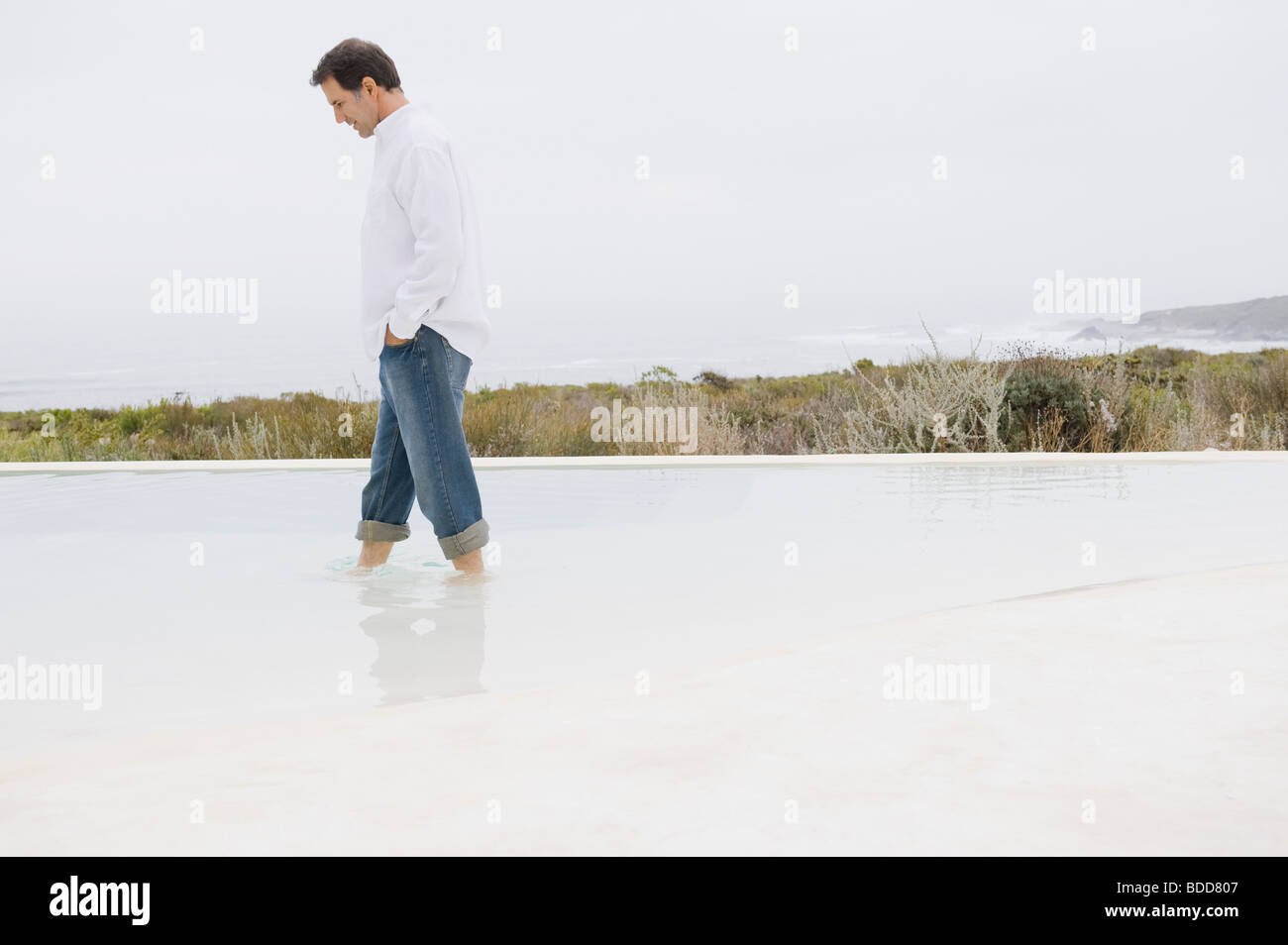 Homme marchant dans une piscine à débordement Banque D'Images