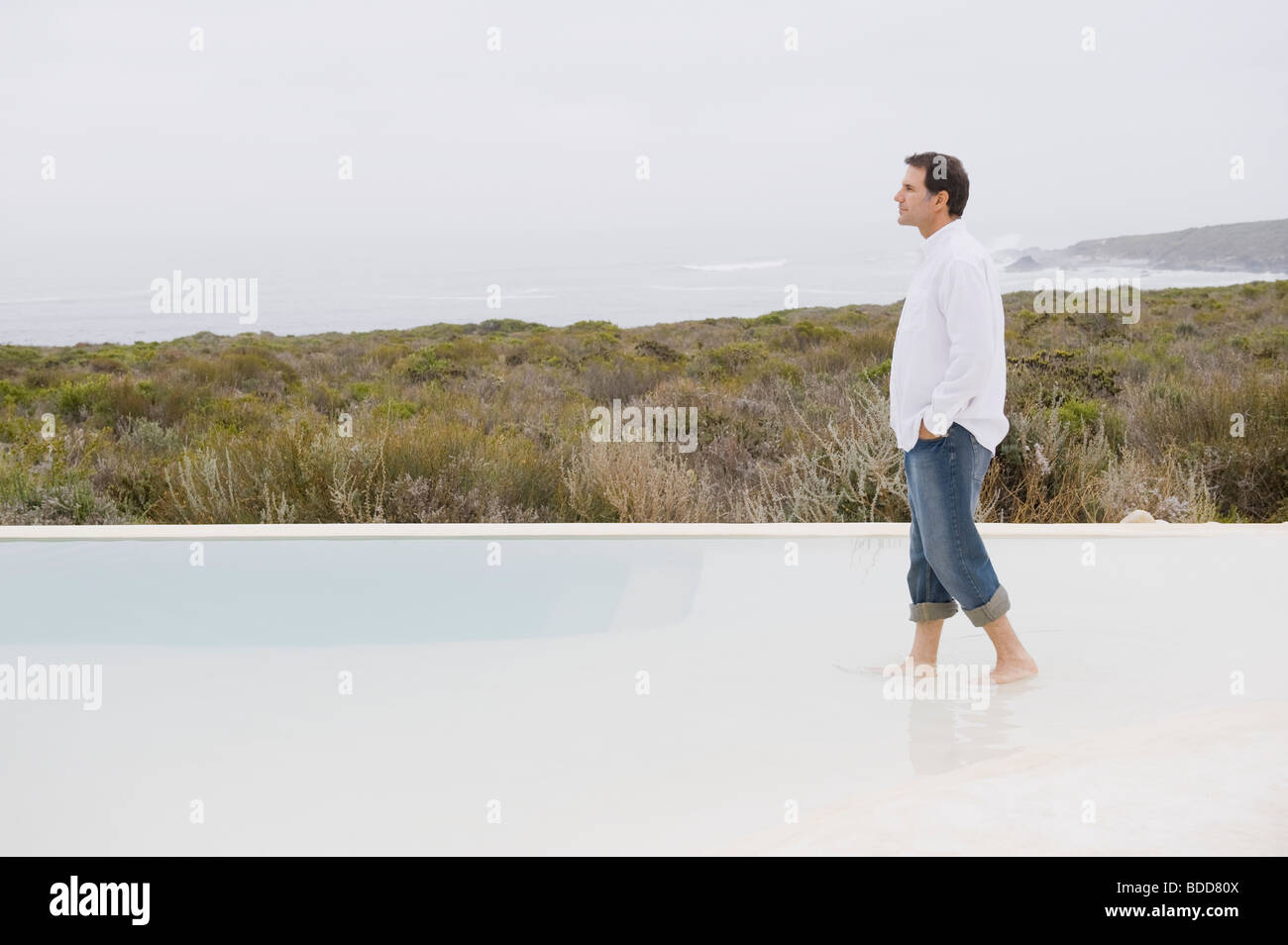 Homme marchant dans une piscine à débordement Banque D'Images