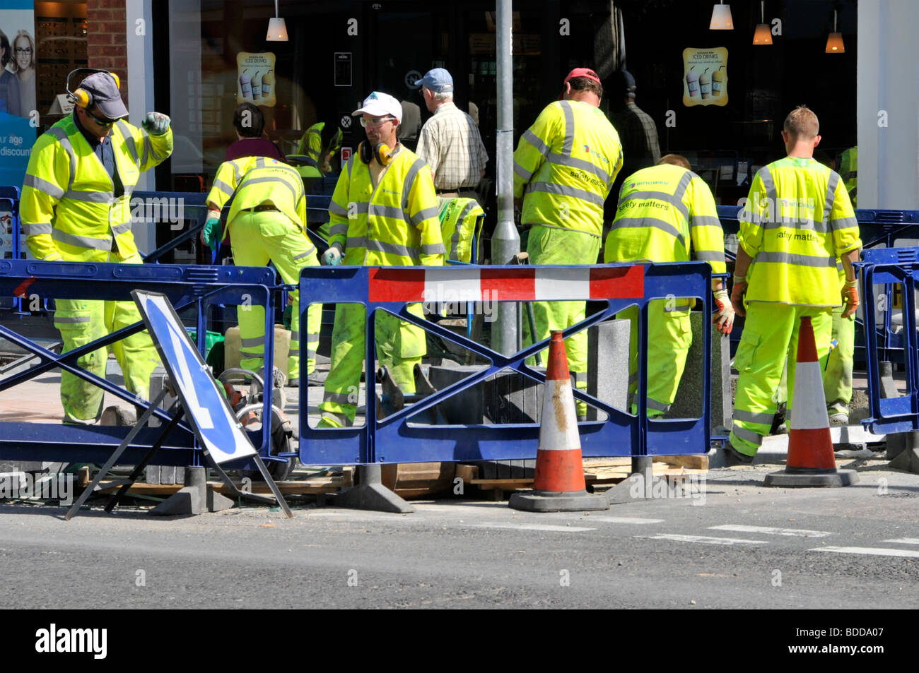 Une foule ou un groupe d'ouvriers qui font du shopping dans une rue en pleine amélioration la route et la chaussée portent une veste haute visibilité qui travaille derrière la sécurité Barrières Angleterre Royaume-Uni Banque D'Images