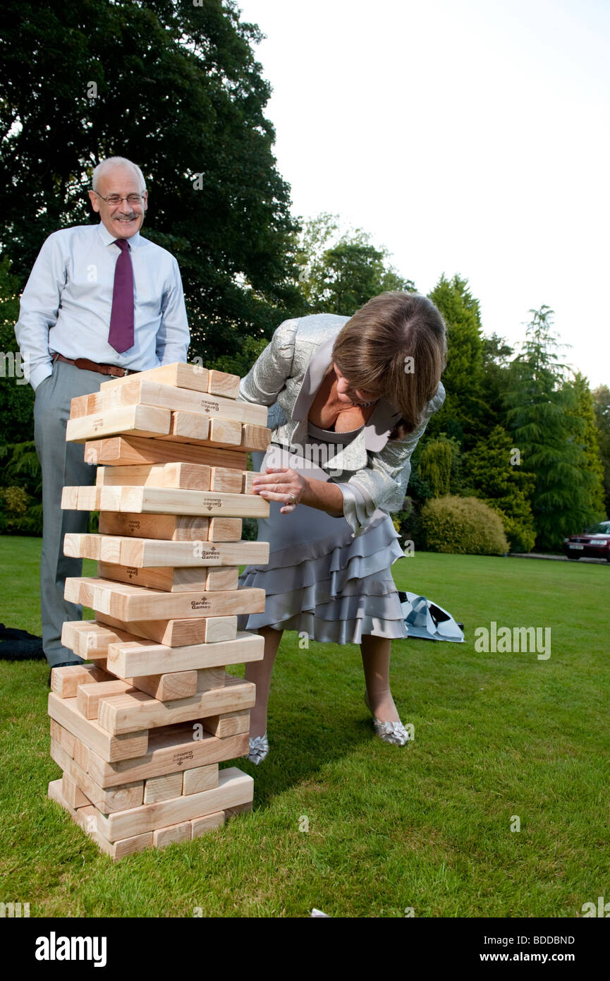 Un couple jouant un jeu de jardin avec une tour Jenga de blocs de bois Banque D'Images