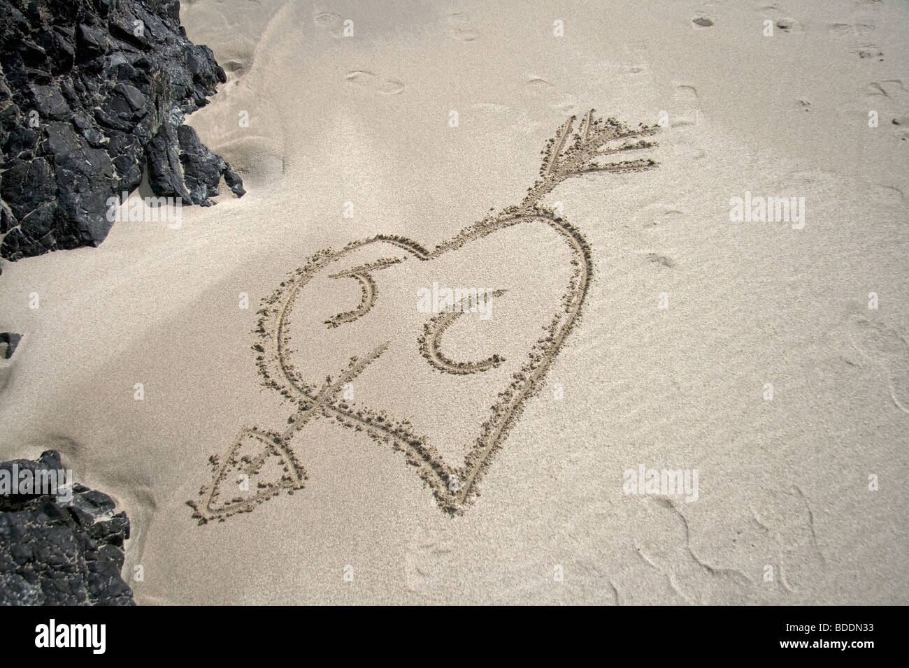 Cœur et les initiales tirées dans le sable Banque D'Images