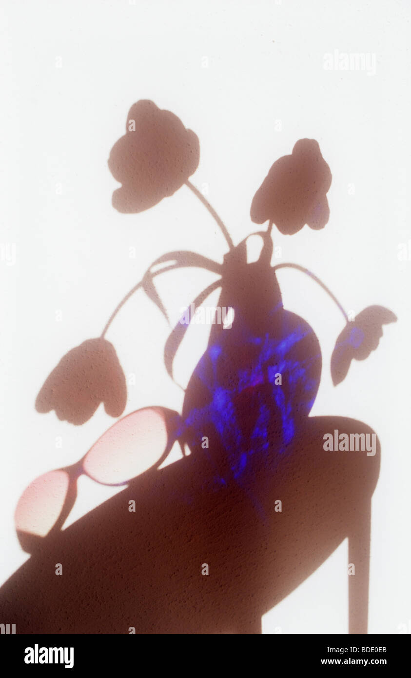 Ombre sur mur blanc de table circulaire avec rose et bleu lunettes ronde vase en verre contenant 4 tulips Banque D'Images Ombre sur mur blanc de table circulaire avec rose et bleu lunettes ronde vase en verre contenant 4 tulips Banque D'Images