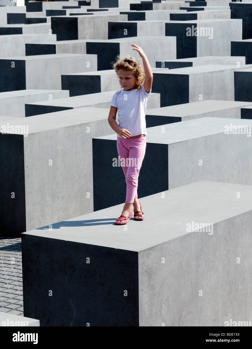 Jeune fille posant sur le dessus de blocs de béton au Mémorial aux Juifs assassinés d'Europe dans le centre de Berlin, Allemagne Banque D'Images