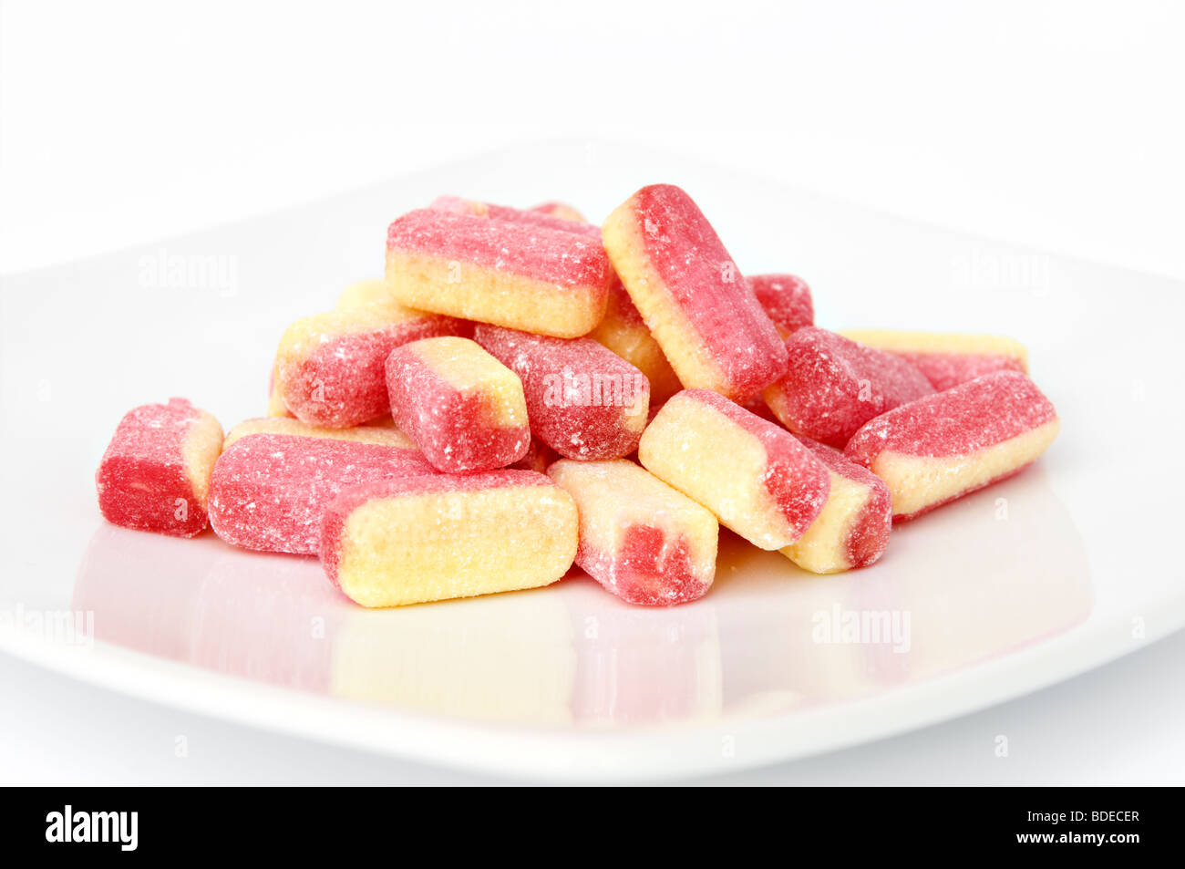 Close up studio shot de la rhubarbe et crème anglaise candy sweets sur plaque blanche avec la réflexion sur un fond blanc. Banque D'Images