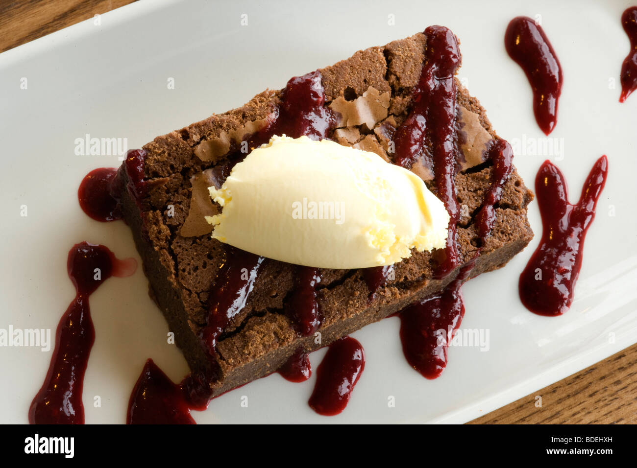 Fudge Brownie tiède avec coulis de framboise et crème caillée Banque D'Images
