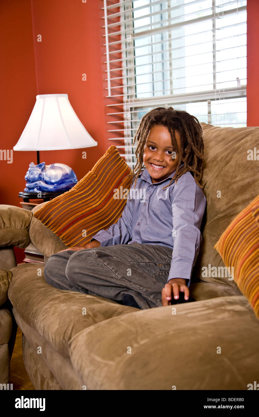 Mixed Race boy sitting on sofa sur séjour Banque D'Images