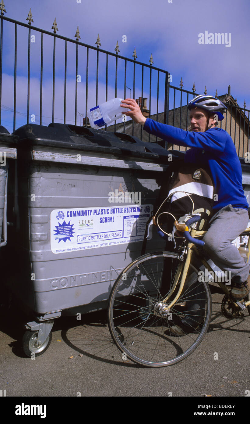 L'homme en vélo avec un sac plein de bouteilles pour le recyclage au point de recyclage Leeds UK Banque D'Images