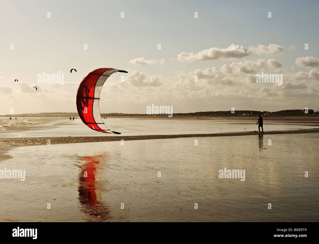 Un parasurfer à pied par la plage de Camber Sands dans l'East Sussex. Banque D'Images