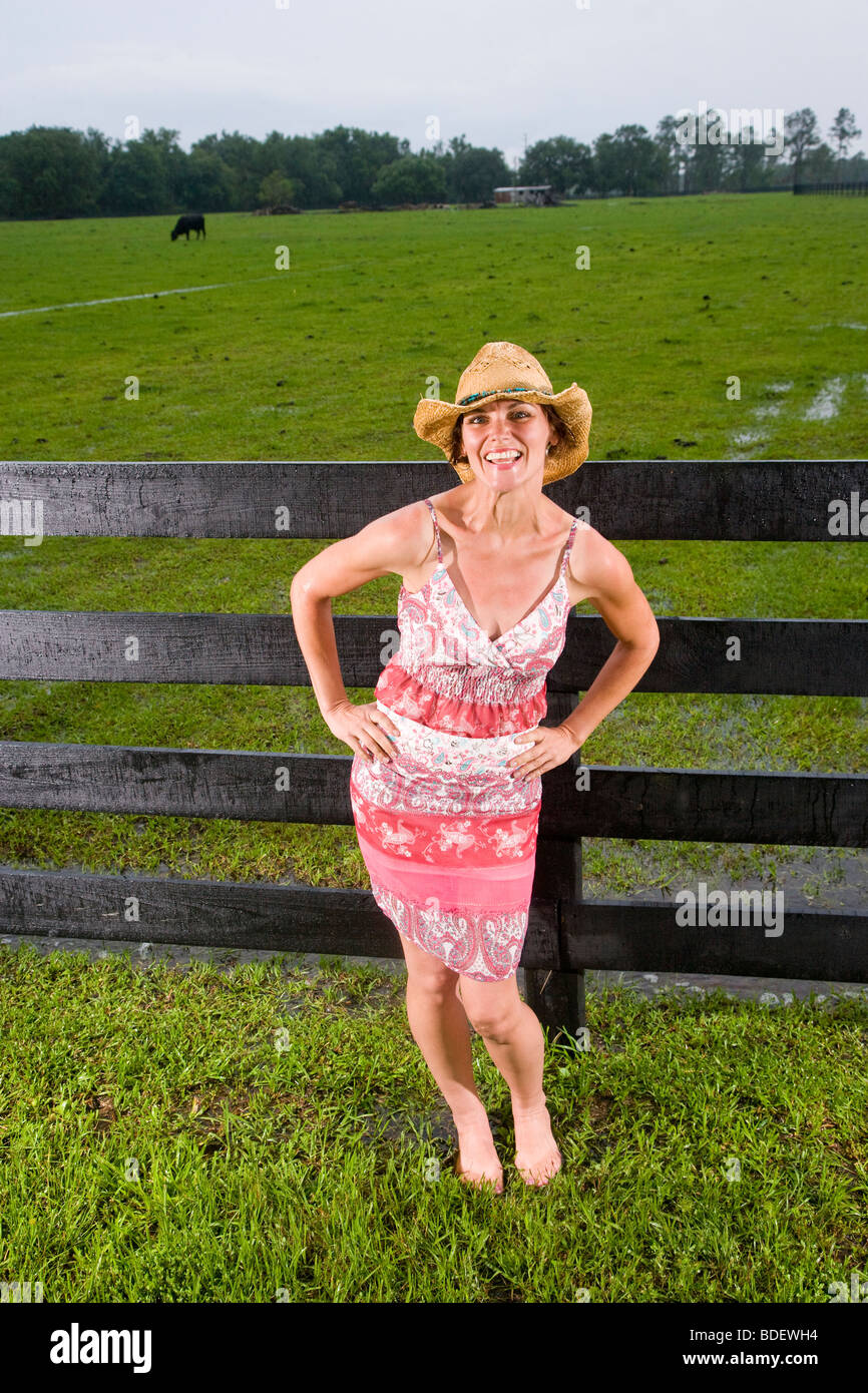 Jolie femme en tenue par une clôture sur ranch Banque D'Images Jolie femme en tenue par une clôture sur ranch Banque D'Images