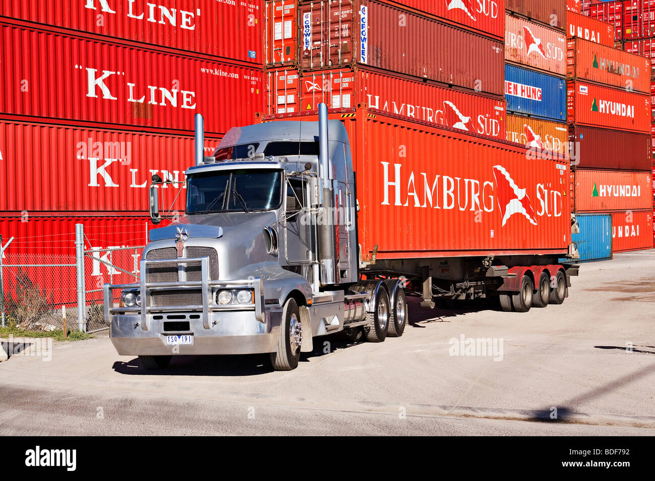 Un camion semi-remorque transporte un conteneur d'un dépôt de conteneurs du port.Le "Port de Melbourne Australie Victoria'. Banque D'Images