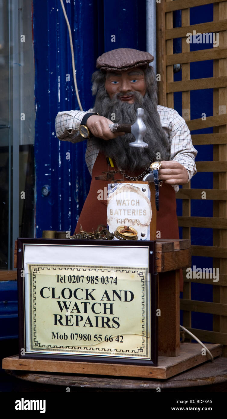 Modèle d'un vieux barbu avec un marteau frappant une montre dans le cadre d'un signe de l'horloge et regardez la publicité des réparations. Banque D'Images