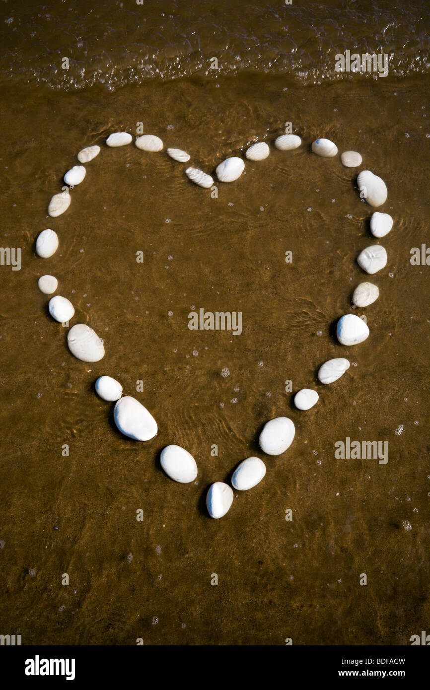 Un coeur dans le sable fabriqués à partir de pierres de craie blanche sur Bridlington la North Beach. La marée montante qui menacent de le submerger. Banque D'Images