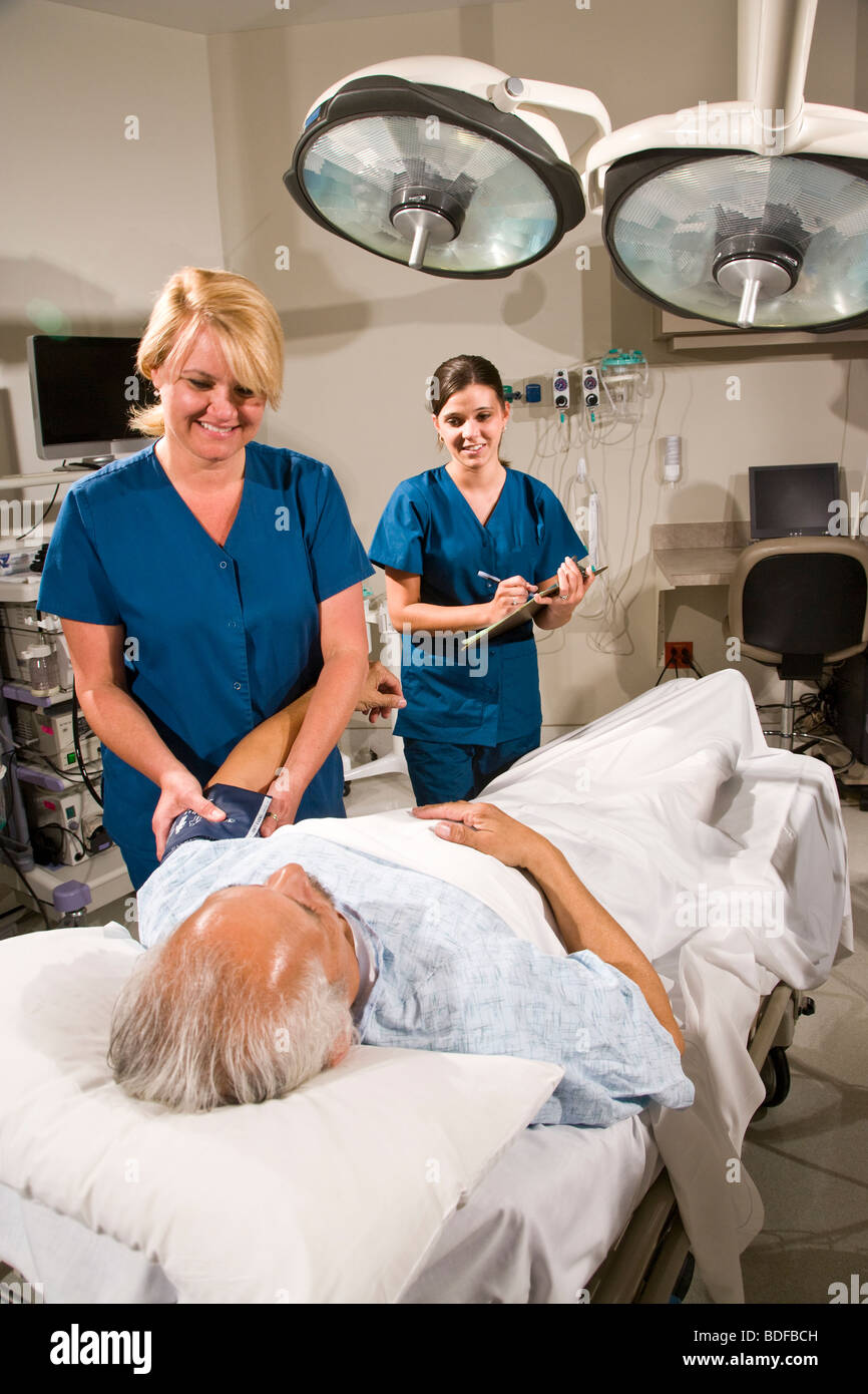 Les infirmières de prendre la tension artérielle du patient in hospital room Banque D'Images