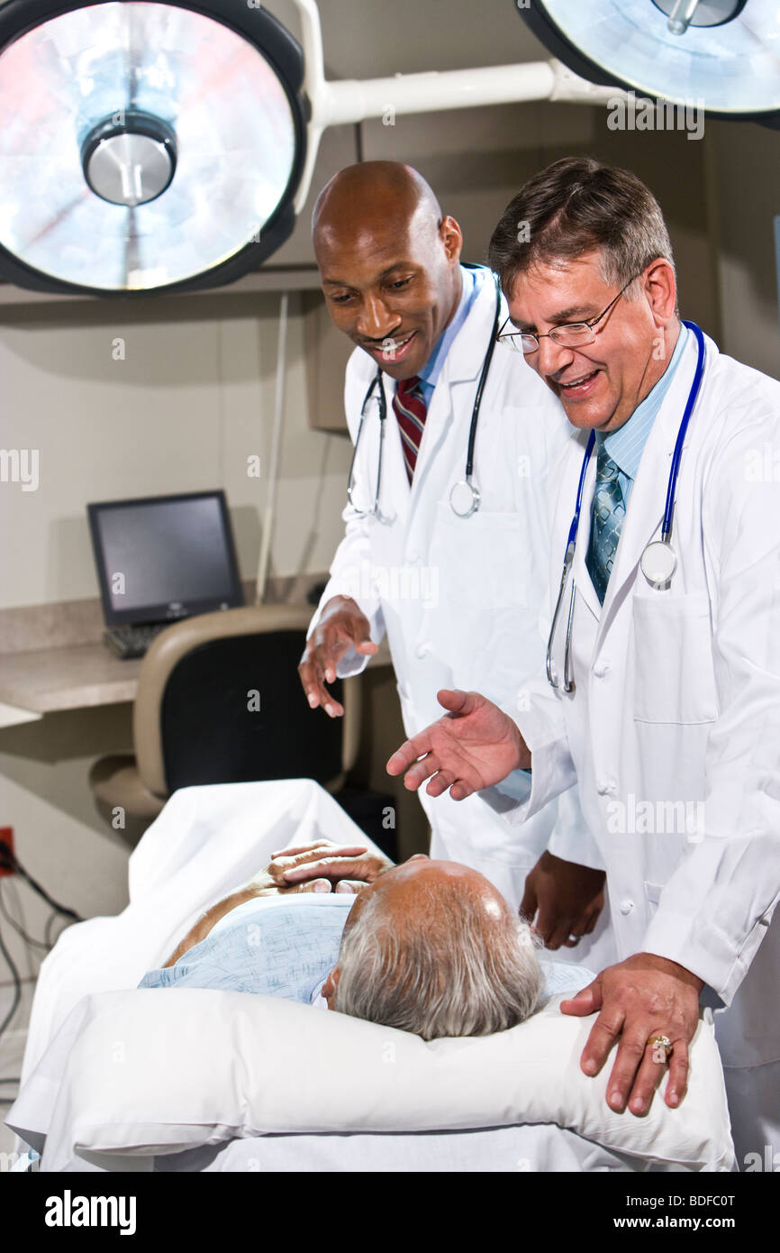 Doctors talking with patient in hospital bed Banque D'Images