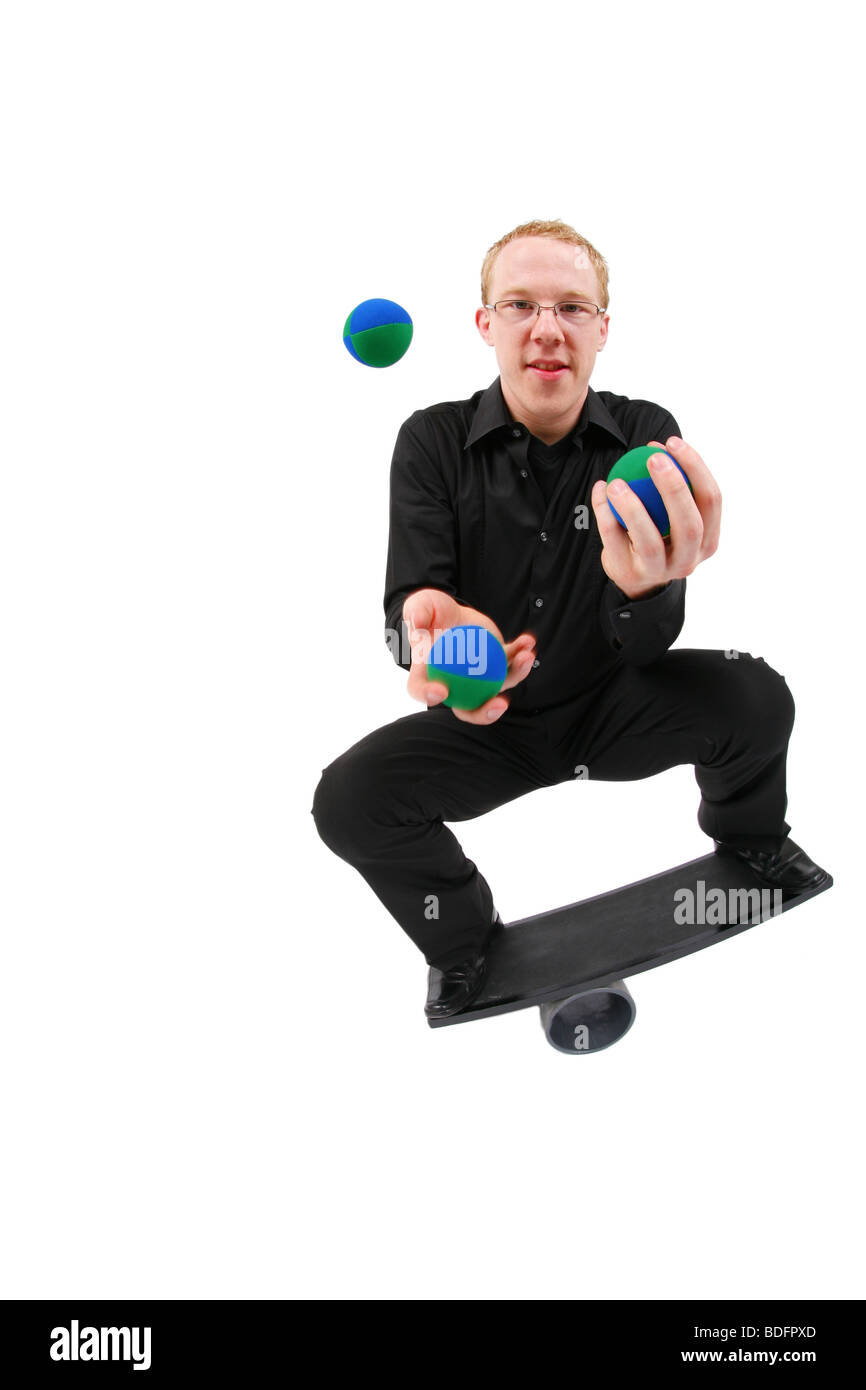Jeune homme jonglant avec des balles et en équilibre sur un rola bola balance board Banque D'Images