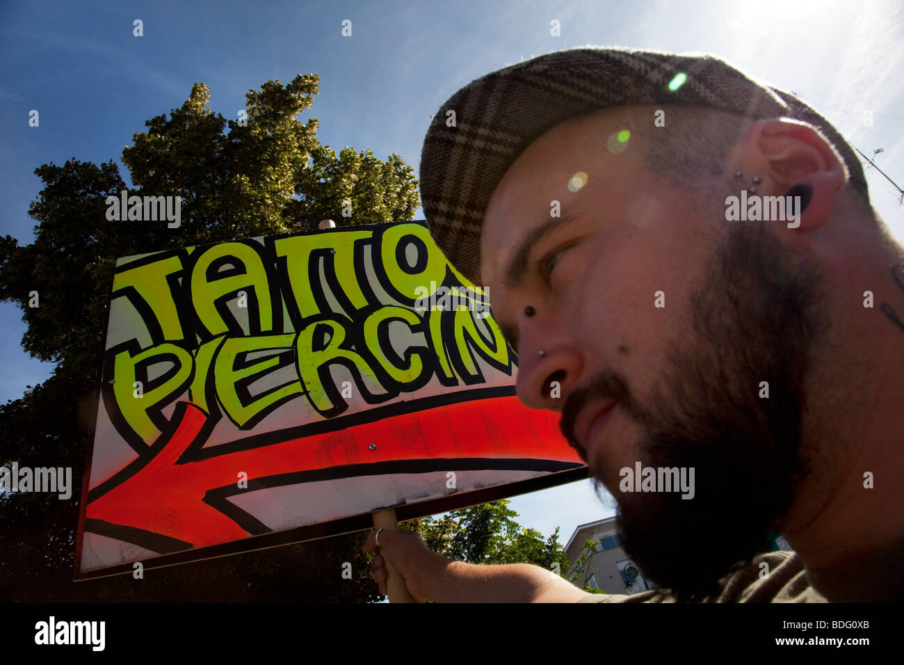 Homme tenant un tatouage et piercing signe sur une journée d'été occupée à Camden, Londres. Banque D'Images