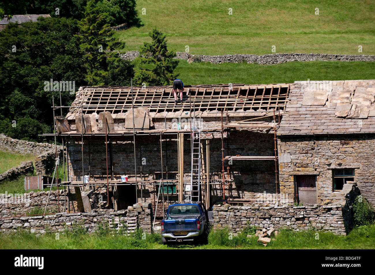 La réparation du toit en pierre de constructeur une grange de Swaledale - Yorkshire Dales National Park. Banque D'Images
