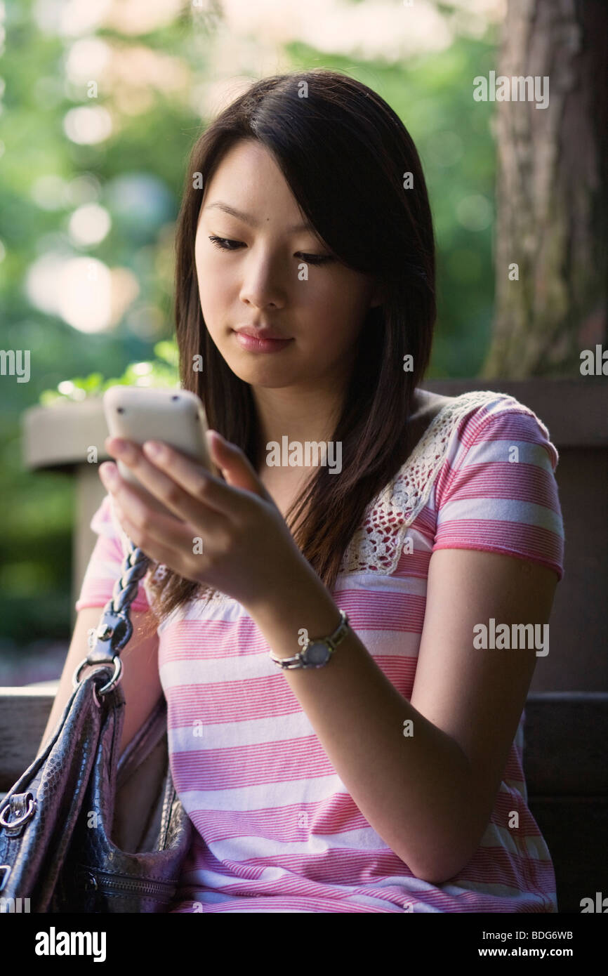 Une jeune femme textos sur son téléphone portable Banque D'Images